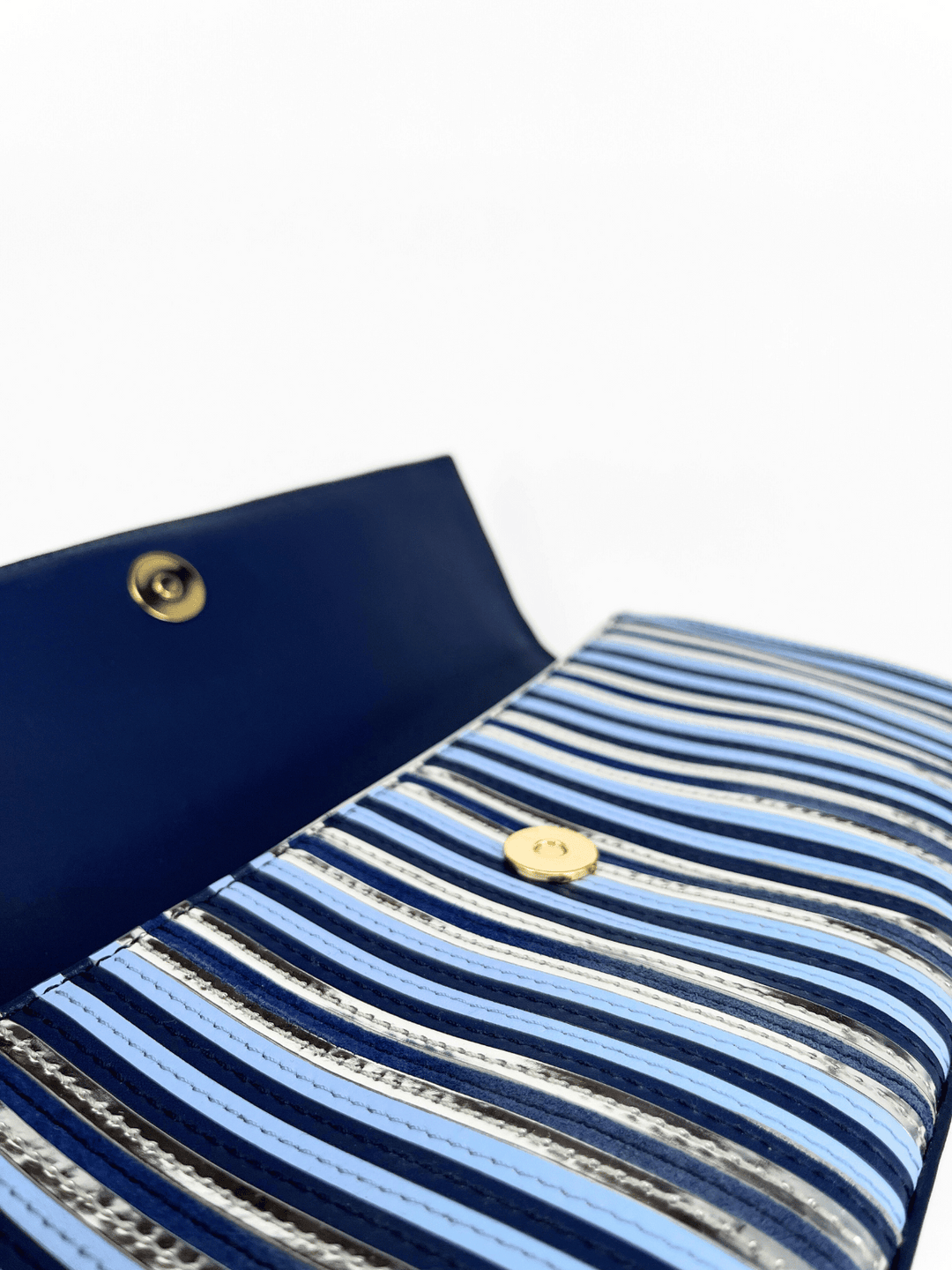 Gestreifte Leder-Clutch von Diane von Furstenberg mit geöffnetem Verschluss in Blau- und Silberfarben.